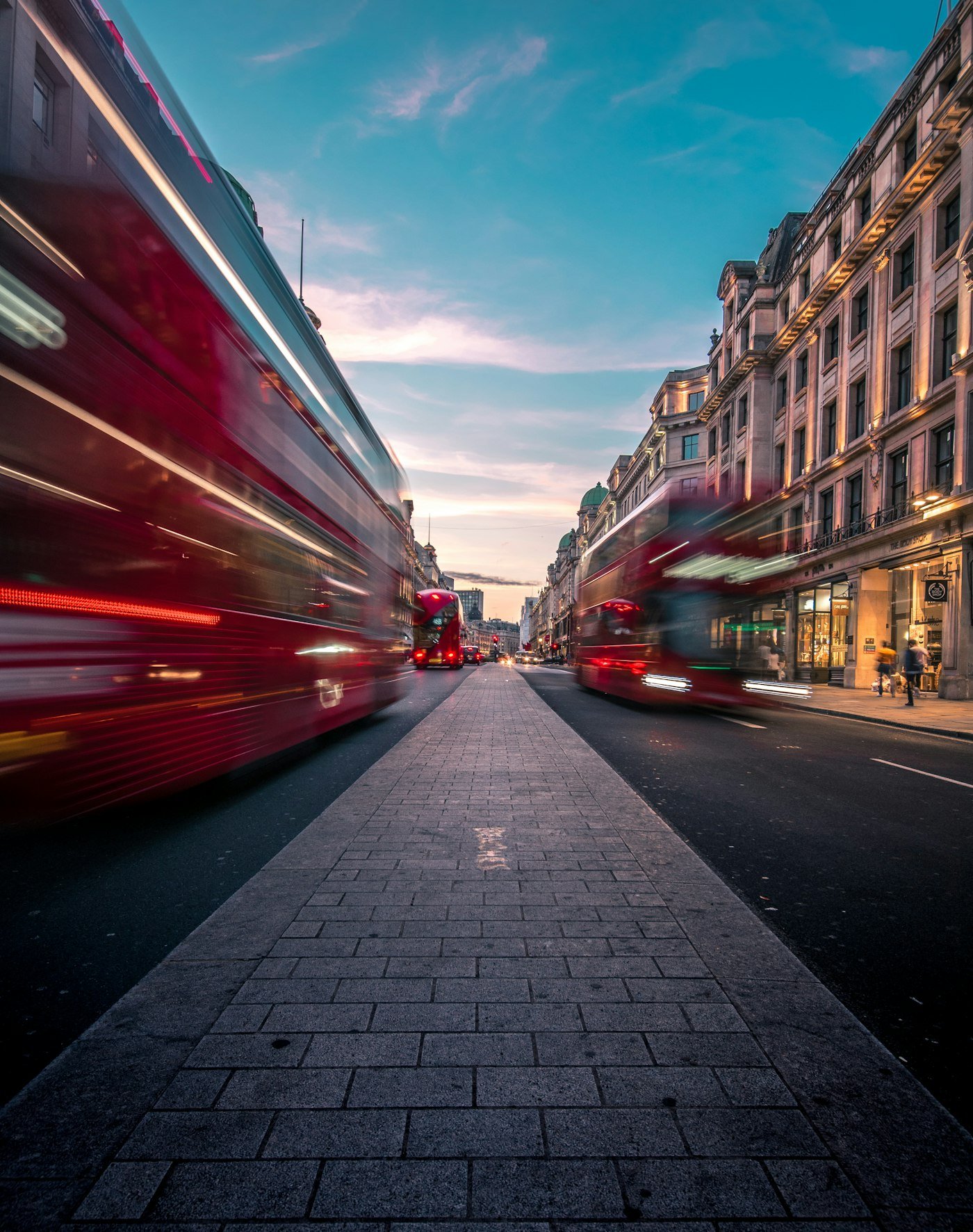 Red London buses on a busy street at dusk