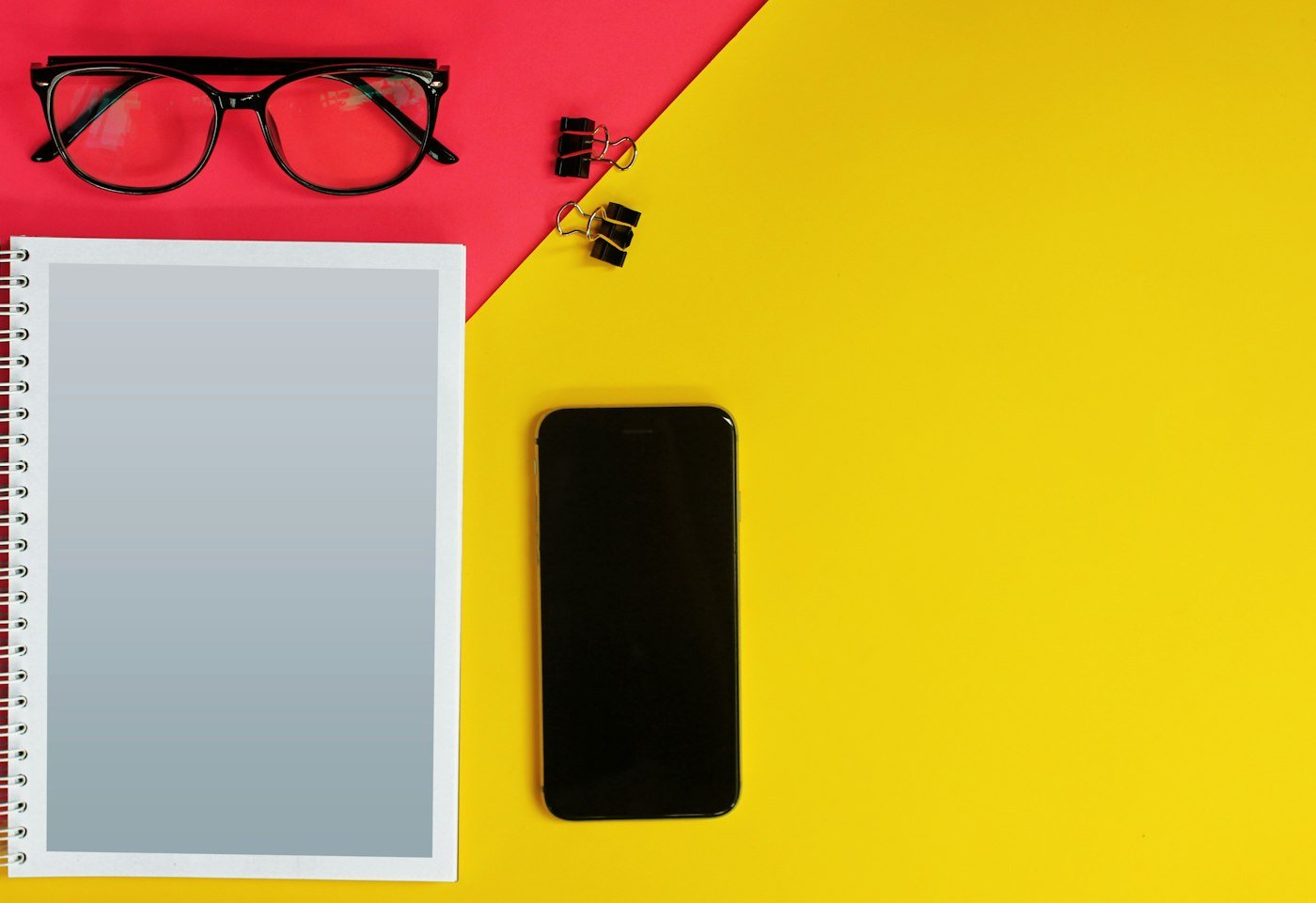 A phone and a notebook on a bright red and yellow desk