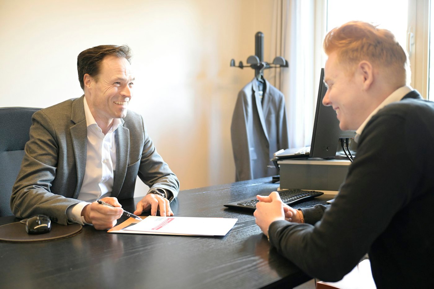 An adviser going through paperwork with a client across a desk