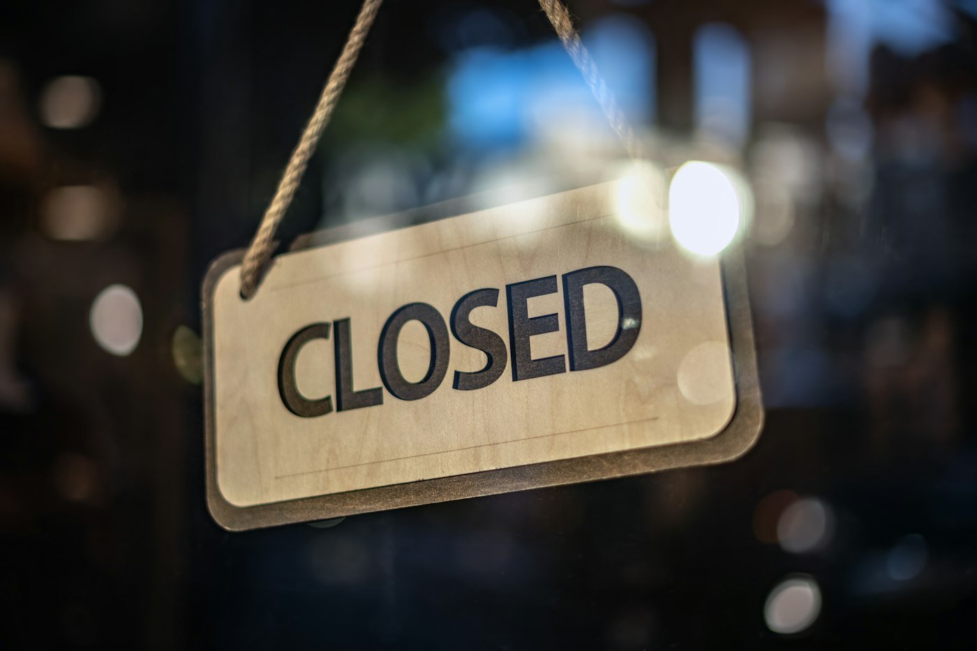 A closed sign hanging on the glass door of a shop