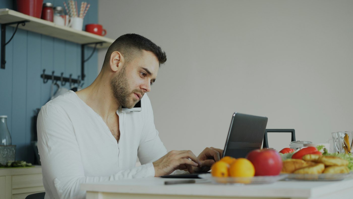 A man working on a laptop at his kitchen table