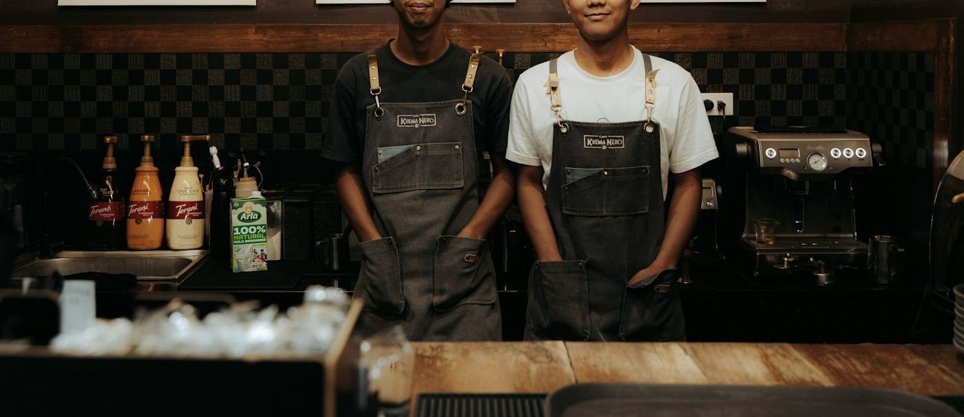 Two staff behind the counter of a small coffee shop