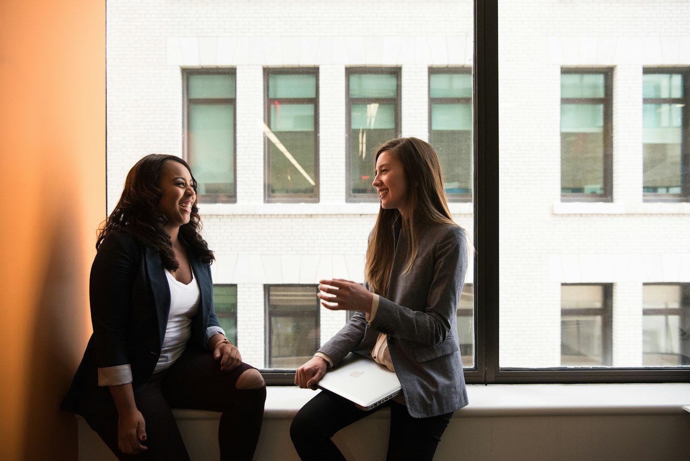 Two women talking by an office window