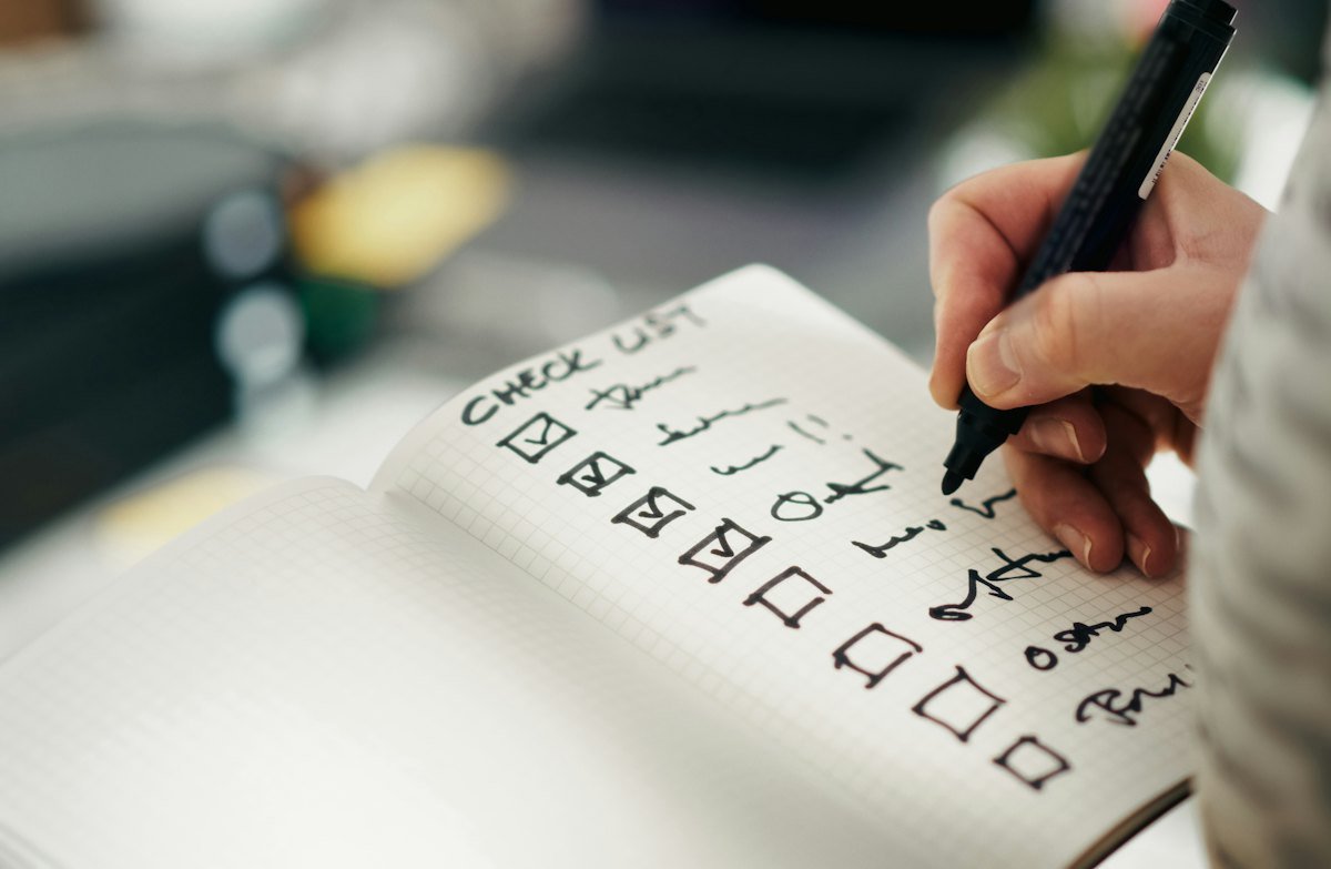 Someone ticking items off a checklist in a notebook