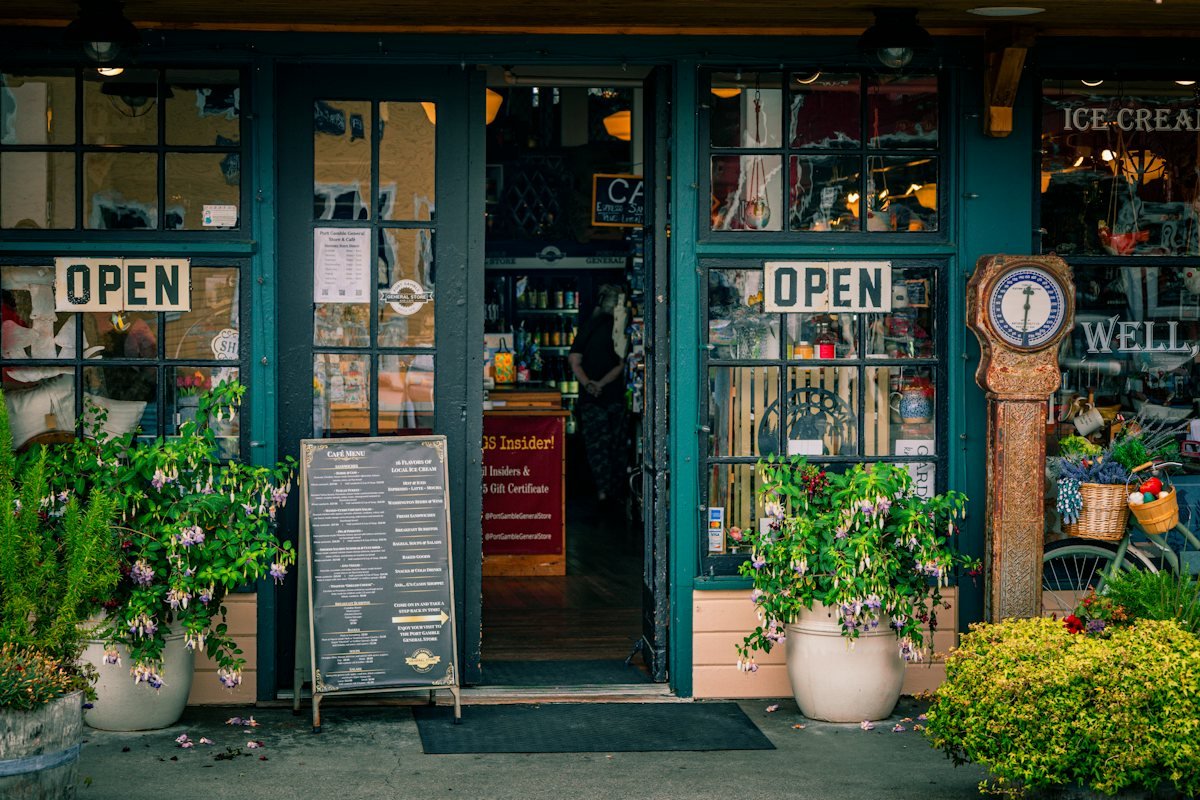 A shop front with open signs, flowers and plants