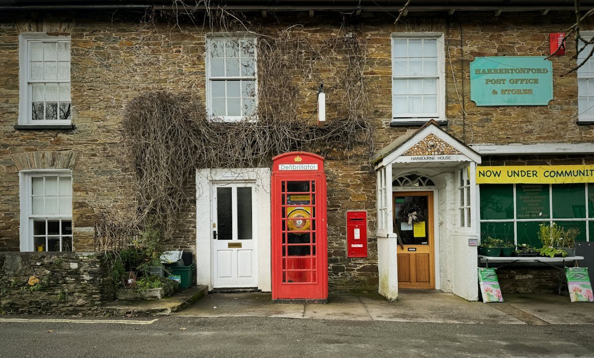 A village post office in England with a red telephone box and a post box
