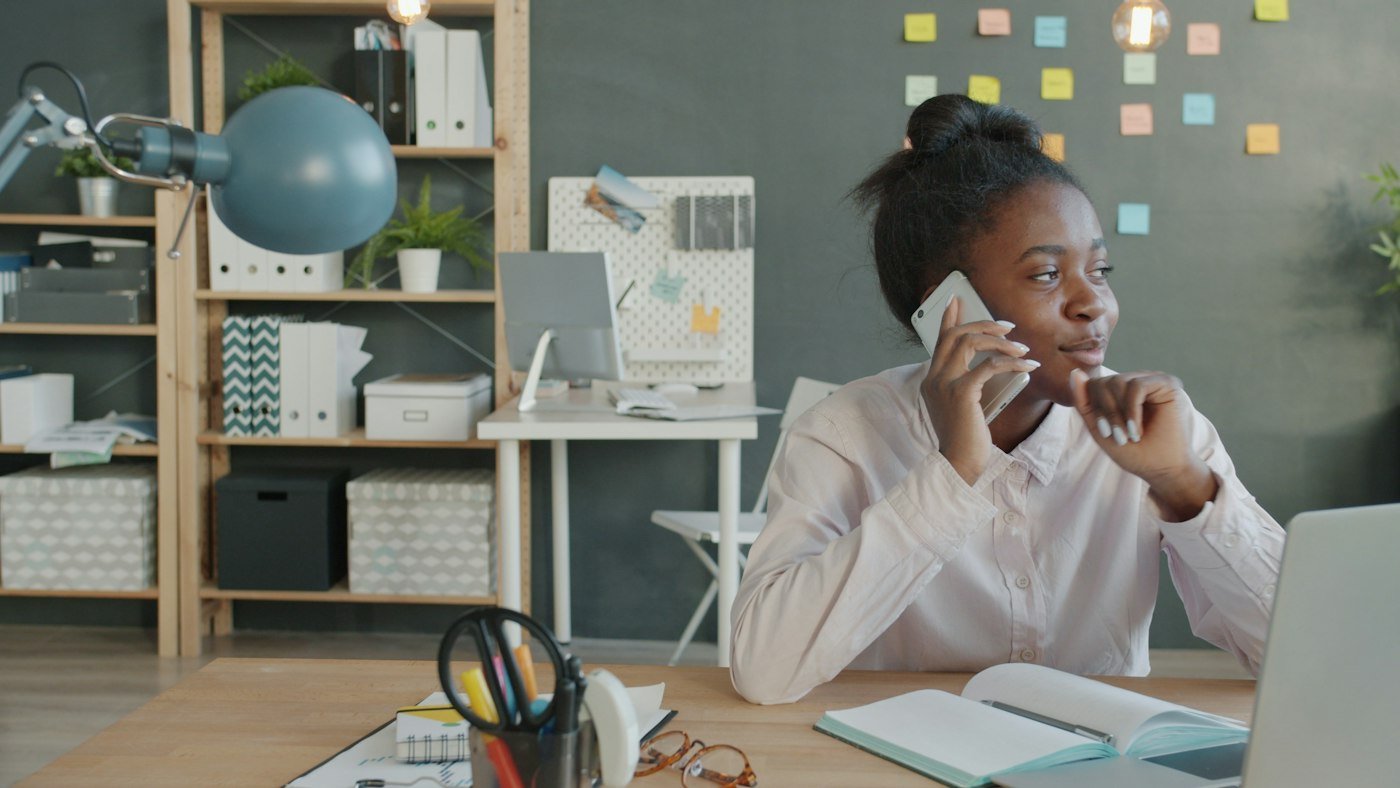 A woman on the phone at her desk, asking a question